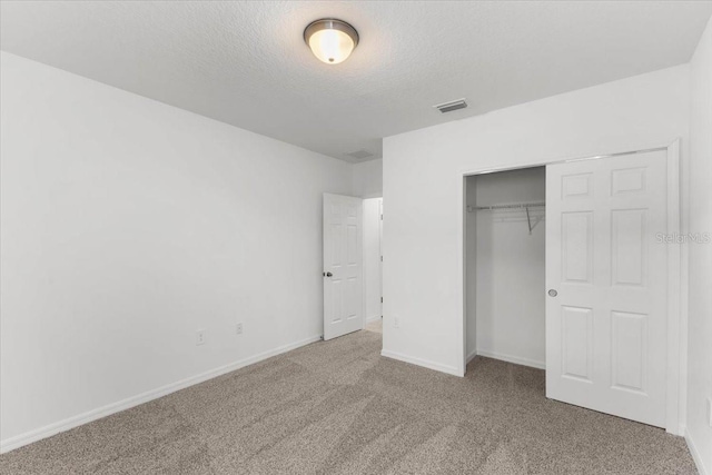 unfurnished bedroom featuring a closet, carpet floors, and a textured ceiling