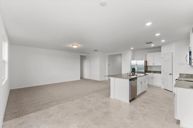 kitchen with an island with sink, sink, white cabinets, light colored carpet, and appliances with stainless steel finishes