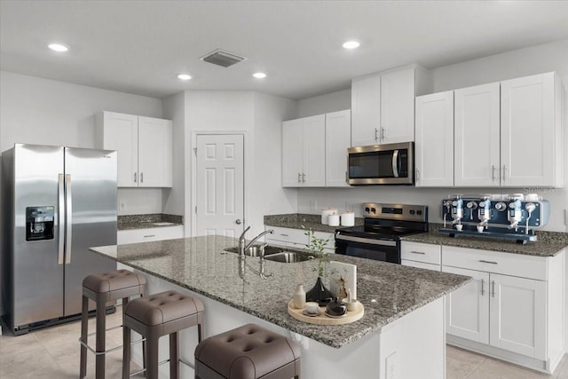 kitchen featuring white cabinets, appliances with stainless steel finishes, sink, and a kitchen island with sink