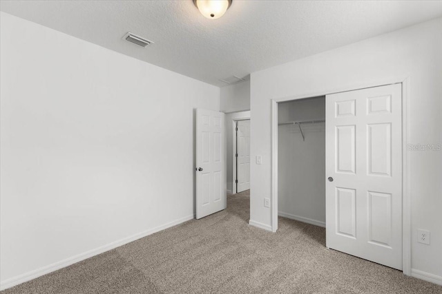 unfurnished bedroom featuring light carpet, a textured ceiling, and a closet