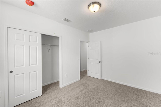 unfurnished bedroom with light carpet, a textured ceiling, and a closet