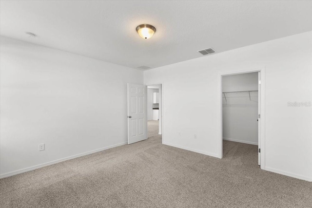 unfurnished bedroom featuring a walk in closet, a closet, and carpet flooring