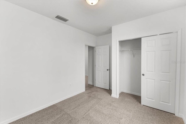 unfurnished bedroom with light colored carpet and a closet