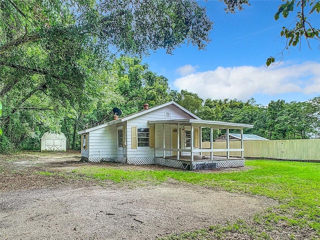 view of front of home with a front yard, covered porch, and a storage shed