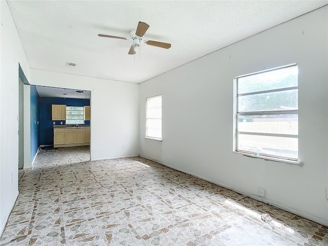 unfurnished room featuring a healthy amount of sunlight, ceiling fan, and light tile floors