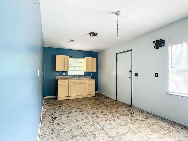 kitchen with cream cabinets, sink, and light tile flooring