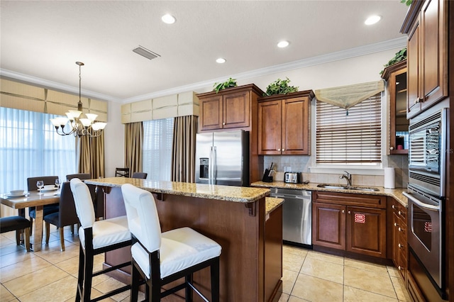 kitchen with decorative light fixtures, a kitchen island, sink, a healthy amount of sunlight, and appliances with stainless steel finishes