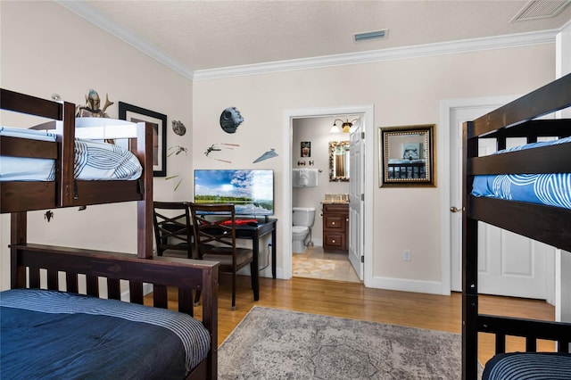 bedroom featuring tile floors, a textured ceiling, ornamental molding, and ensuite bath