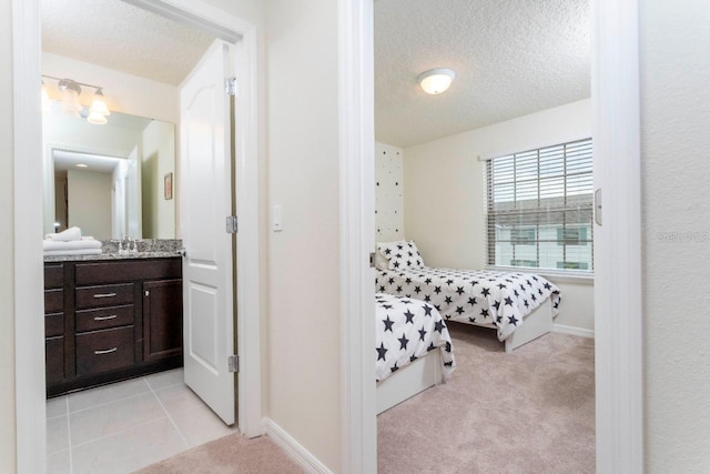 bedroom with light carpet, sink, and a textured ceiling