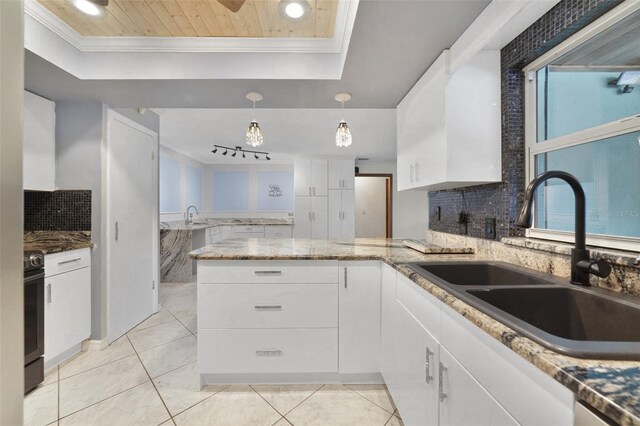 kitchen with light tile patterned floors, backsplash, sink, and kitchen peninsula