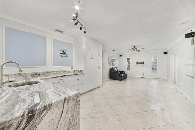 kitchen with sink, white cabinetry, light stone countertops, ceiling fan, and crown molding