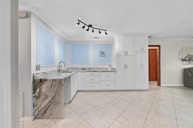 kitchen with light tile patterned floors, ornamental molding, rail lighting, light stone countertops, and white cabinetry