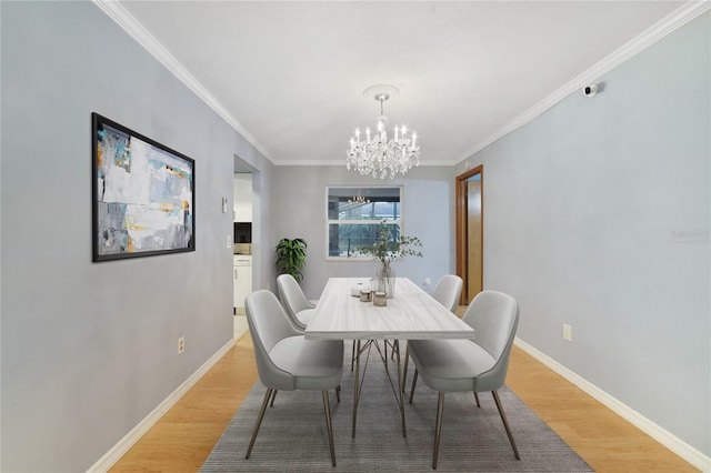 dining space with light wood-type flooring, an inviting chandelier, and ornamental molding