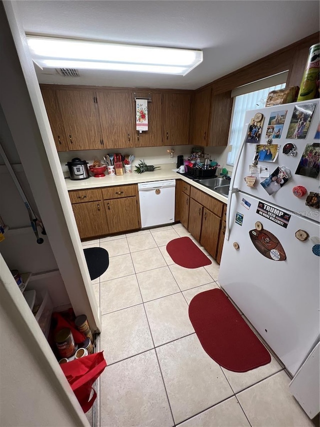 kitchen with sink, white appliances, and light tile floors