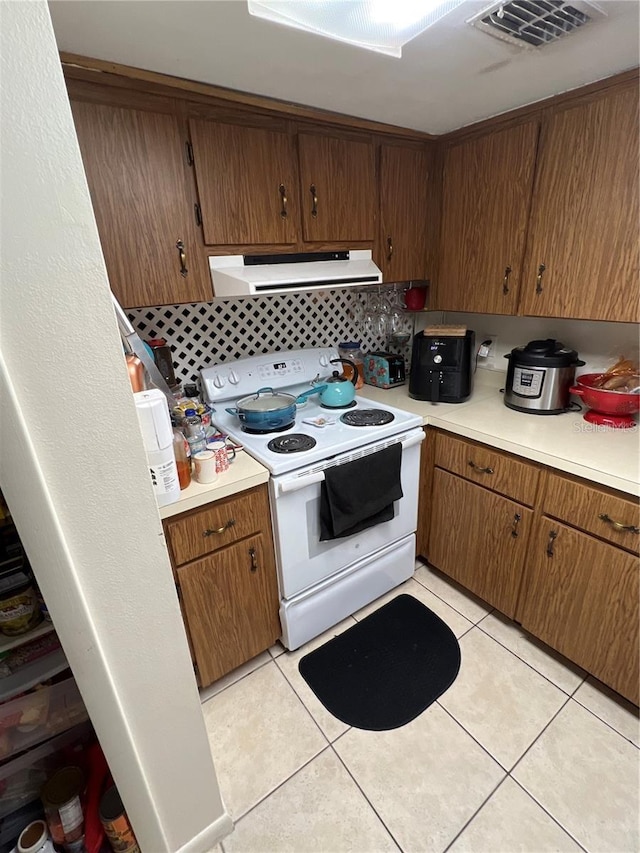 kitchen featuring white electric stove, backsplash, and light tile floors