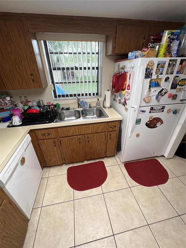 kitchen featuring white appliances, sink, and light tile floors