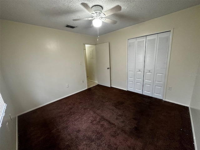 unfurnished bedroom featuring a textured ceiling, carpet floors, visible vents, baseboards, and a closet