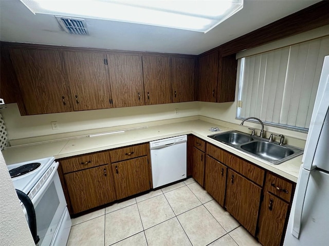 kitchen featuring light tile patterned floors, light countertops, visible vents, a sink, and white appliances