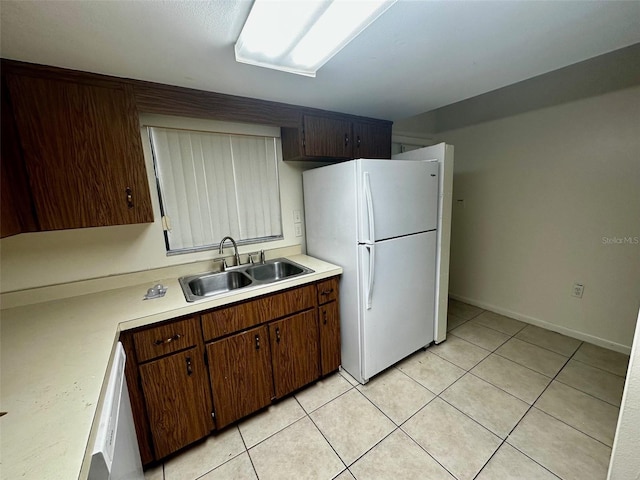 kitchen featuring white appliances, light tile patterned floors, light countertops, and a sink