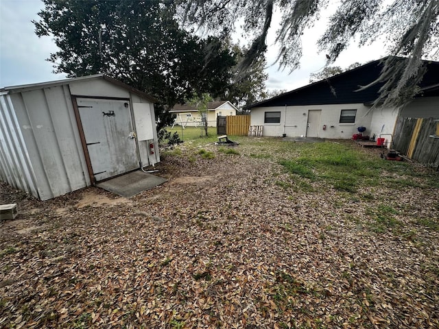 view of yard with a shed, fence, and an outbuilding