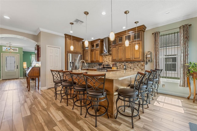 kitchen featuring light hardwood / wood-style flooring, stove, stainless steel refrigerator with ice dispenser, and wall chimney exhaust hood