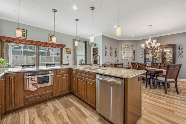 kitchen featuring hanging light fixtures, light hardwood / wood-style flooring, appliances with stainless steel finishes, light stone counters, and sink