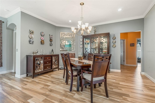 dining space with crown molding, an inviting chandelier, and light hardwood / wood-style flooring