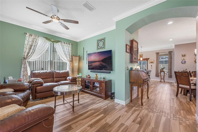 living room featuring wood-type flooring, ceiling fan, a textured ceiling, and crown molding