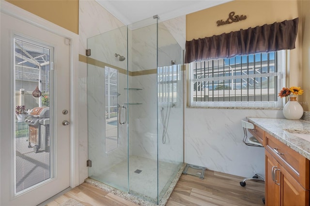 bathroom featuring tile walls, a shower with shower door, hardwood / wood-style flooring, and vanity