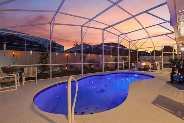 pool at dusk featuring a lanai and a patio area