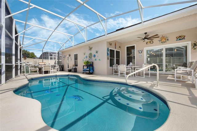 view of swimming pool with glass enclosure, a patio area, and ceiling fan