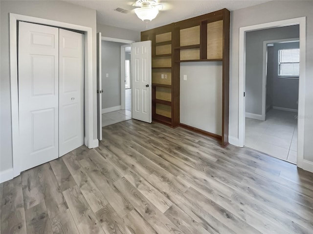 unfurnished bedroom with a closet, light hardwood / wood-style flooring, and ceiling fan