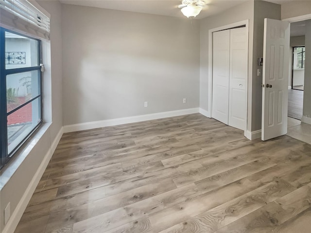 unfurnished bedroom with multiple windows, a closet, and light wood-type flooring