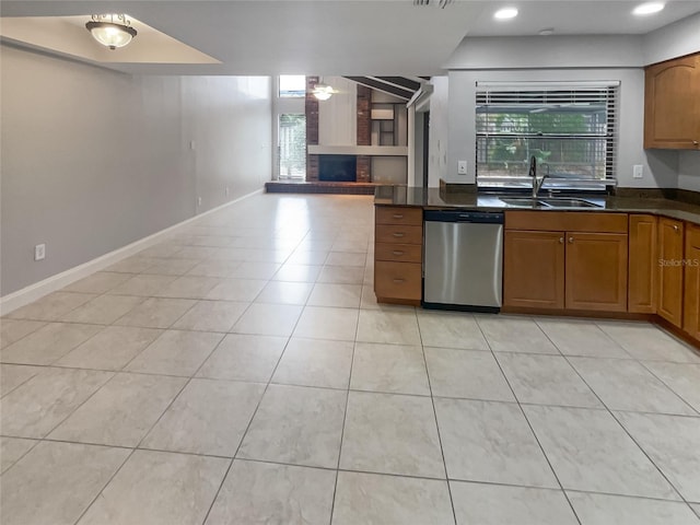 kitchen featuring a fireplace, sink, light tile patterned floors, and stainless steel dishwasher