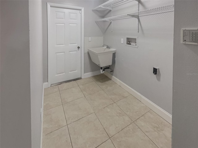 clothes washing area featuring sink, light tile patterned floors, and washer hookup