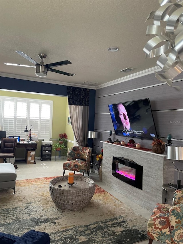 living room featuring crown molding, tile patterned flooring, ceiling fan, a fireplace, and a textured ceiling