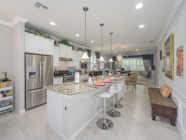 kitchen with appliances with stainless steel finishes, a large island with sink, crown molding, and recessed lighting