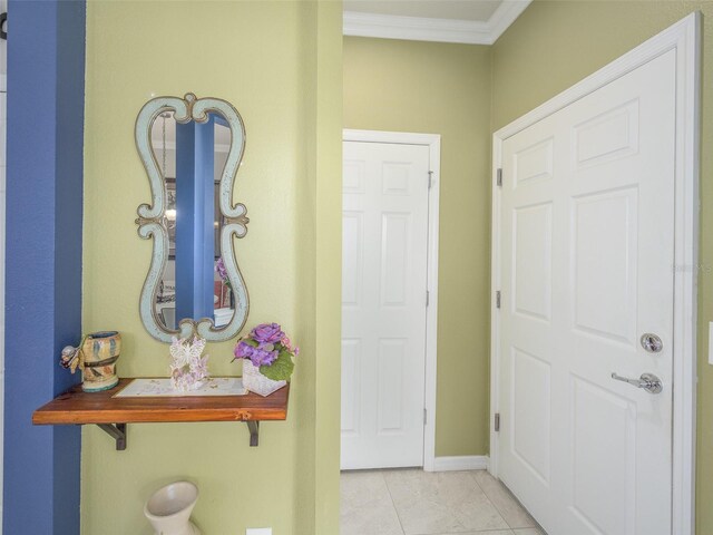 foyer entrance with crown molding, light tile patterned flooring, and baseboards