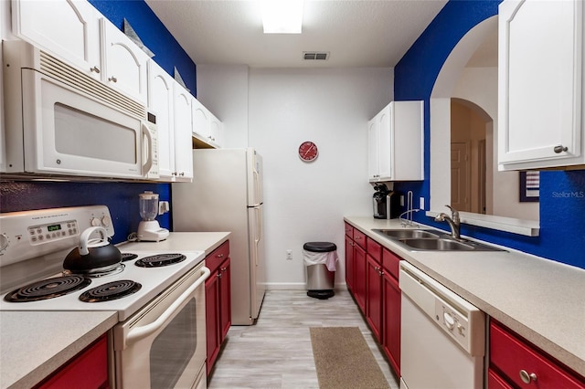 kitchen with sink, white appliances, white cabinetry, and light wood-type flooring