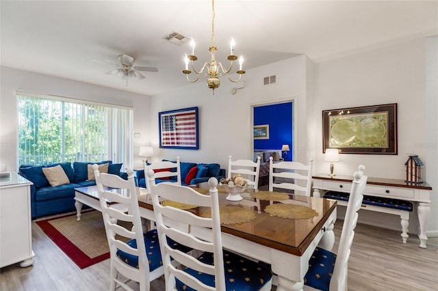 dining area with ceiling fan with notable chandelier and light hardwood / wood-style floors