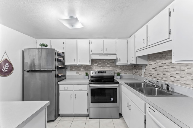 kitchen with appliances with stainless steel finishes, white cabinets, backsplash, and light tile floors