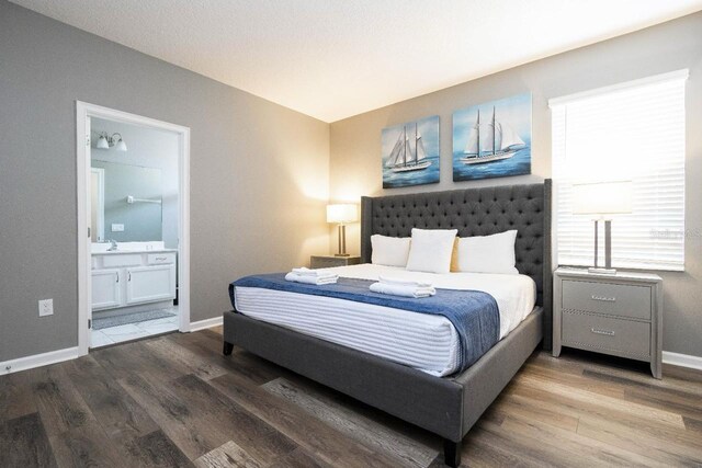 bedroom with wood-type flooring, sink, and ensuite bath