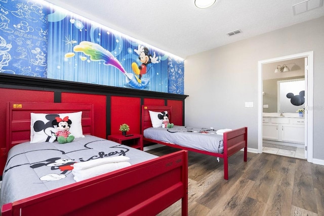 bedroom with ensuite bathroom, dark hardwood / wood-style flooring, and a textured ceiling