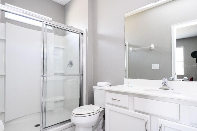 bathroom with an enclosed shower, vanity, and toilet