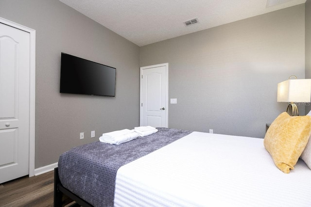 bedroom with dark hardwood / wood-style floors and a closet