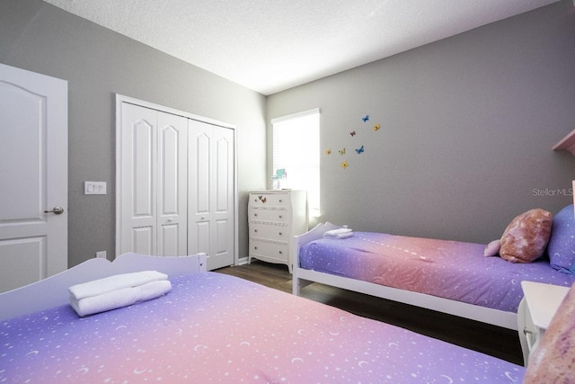 bedroom featuring a closet, a textured ceiling, and dark wood-type flooring