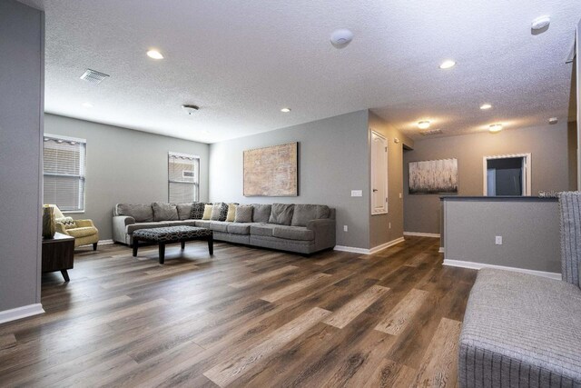 living room with a textured ceiling and dark wood-type flooring