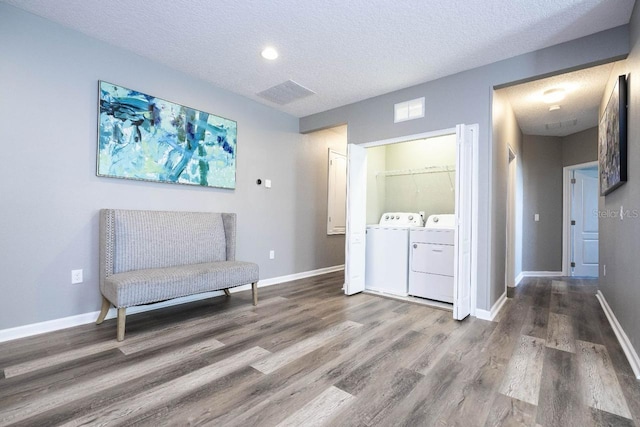 living area with hardwood / wood-style flooring, washing machine and dryer, and a textured ceiling