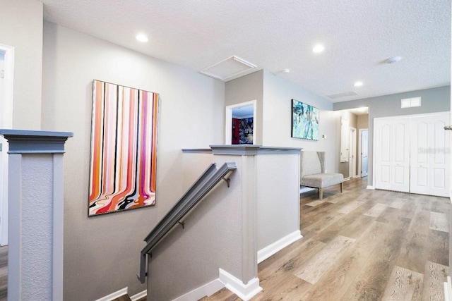 stairway featuring a textured ceiling and light wood-type flooring