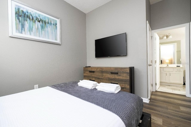 bedroom with sink, ensuite bath, vaulted ceiling, and dark hardwood / wood-style flooring